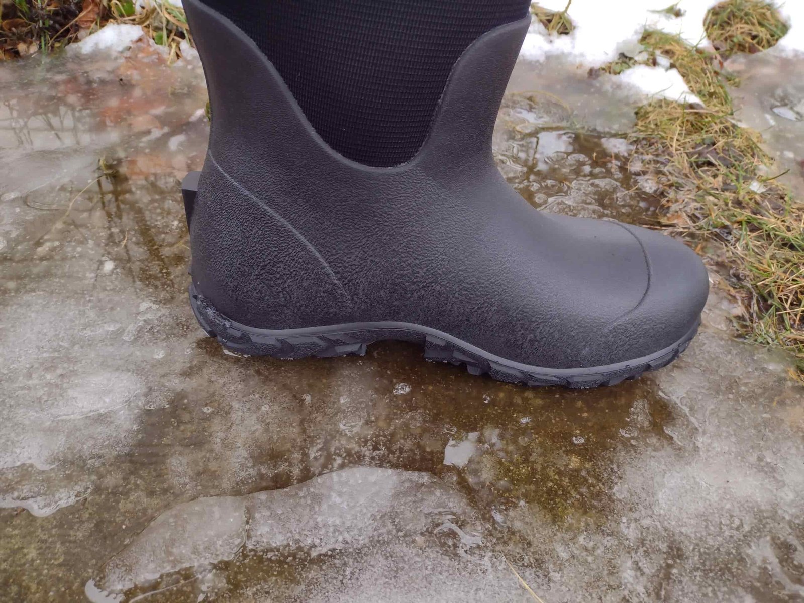 Ground level view of someone wearing the black Bogs Workman on ice.
