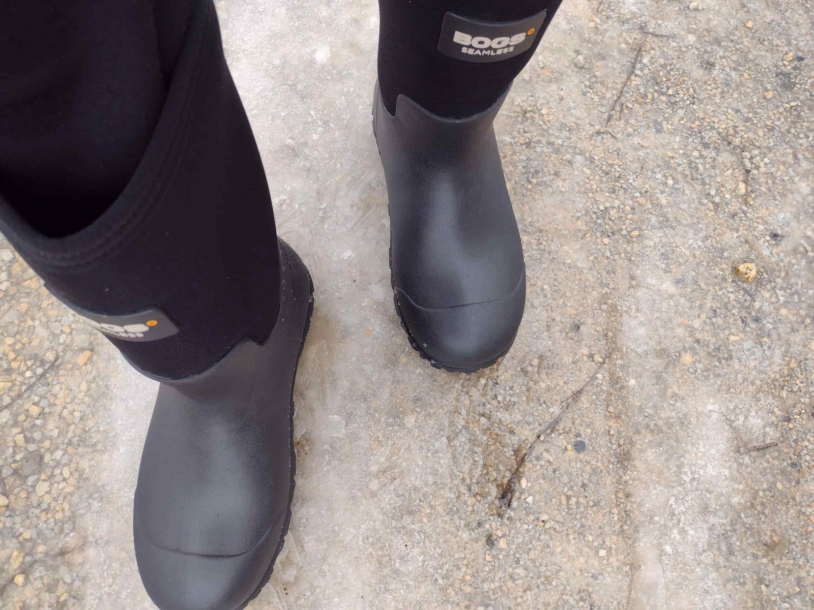 Ground level view of someone wearing the black Bogs Workman on ice.
