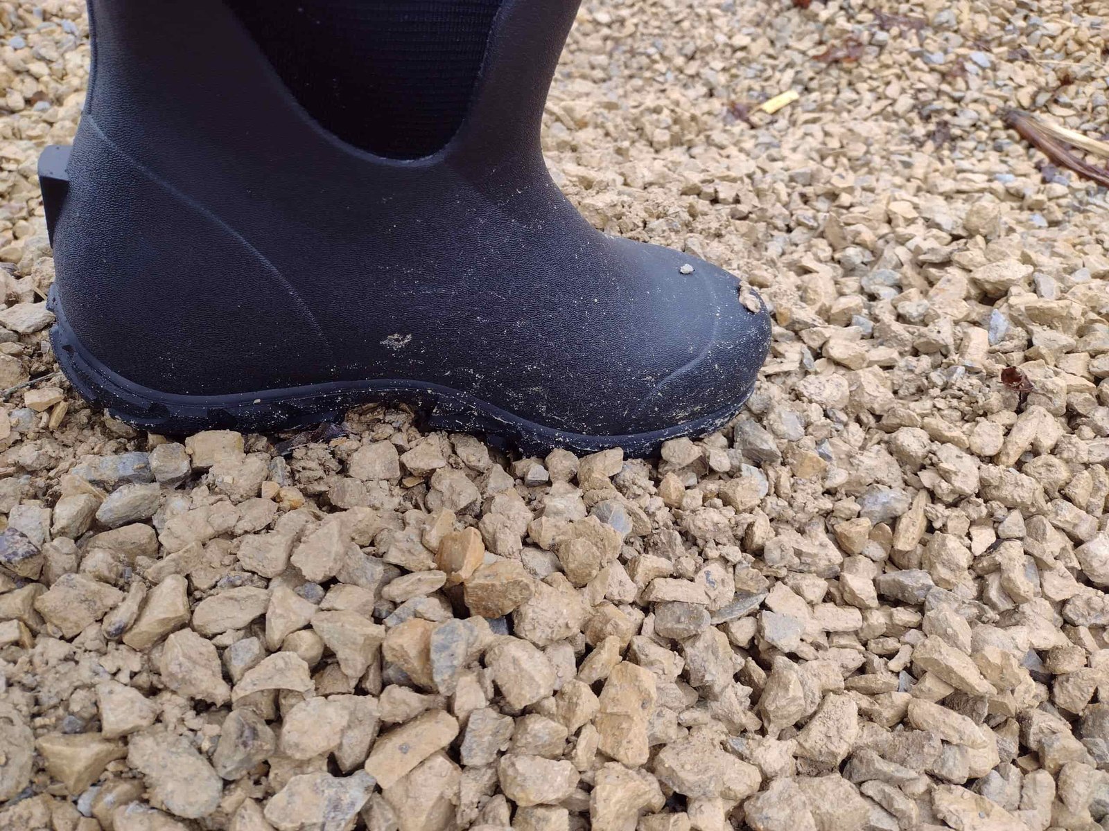 Ground level view of someone wearing the black Bogs Workman in muddy snow and water.