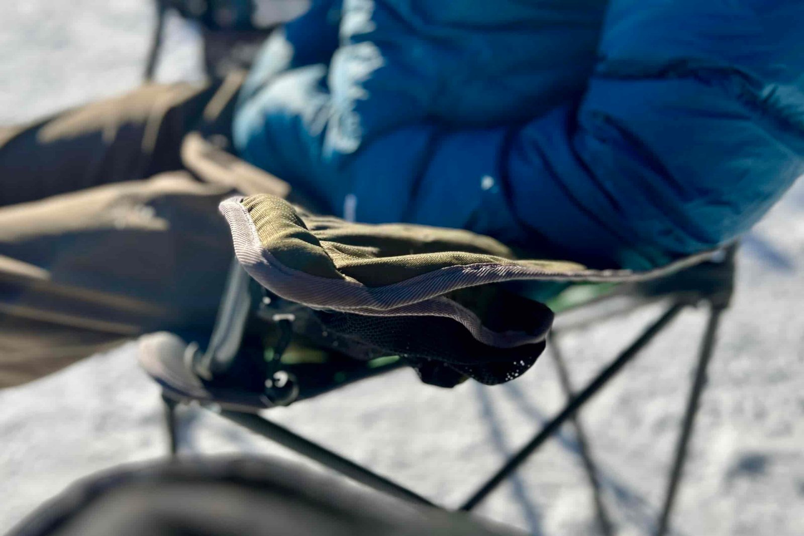 Close up of a person's elbow resting on an armrest of a camping chair.