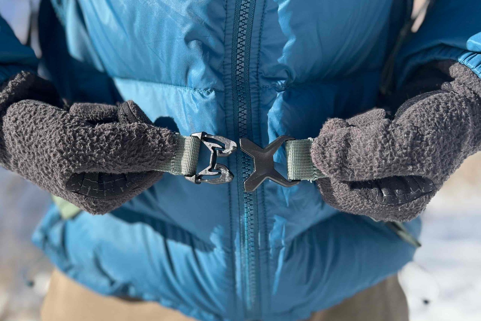 Close up of a person buckling the waist straps of a daypack.