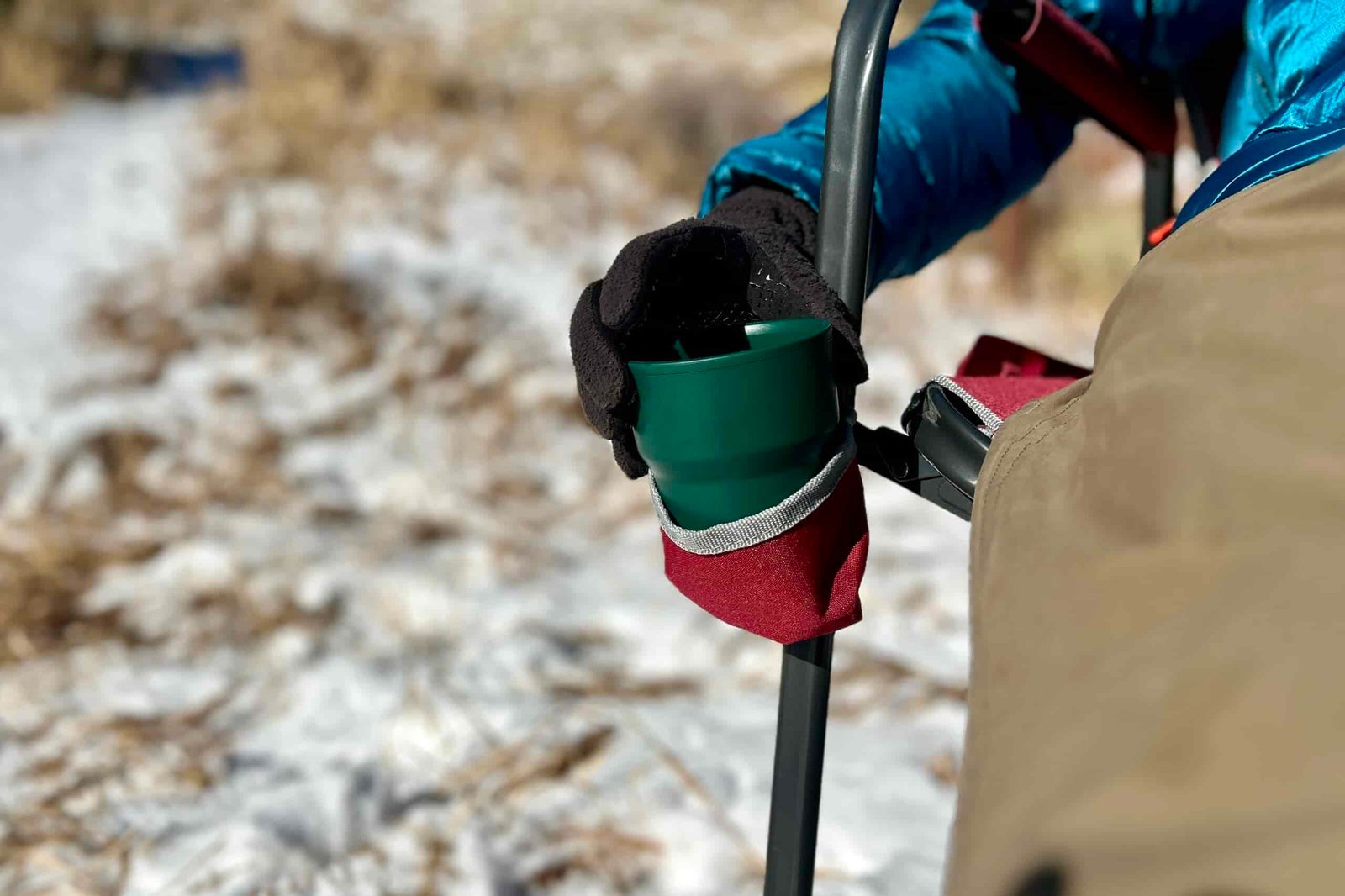 Close up of a person placing a mug in a fabric cupholder of a camping chair.