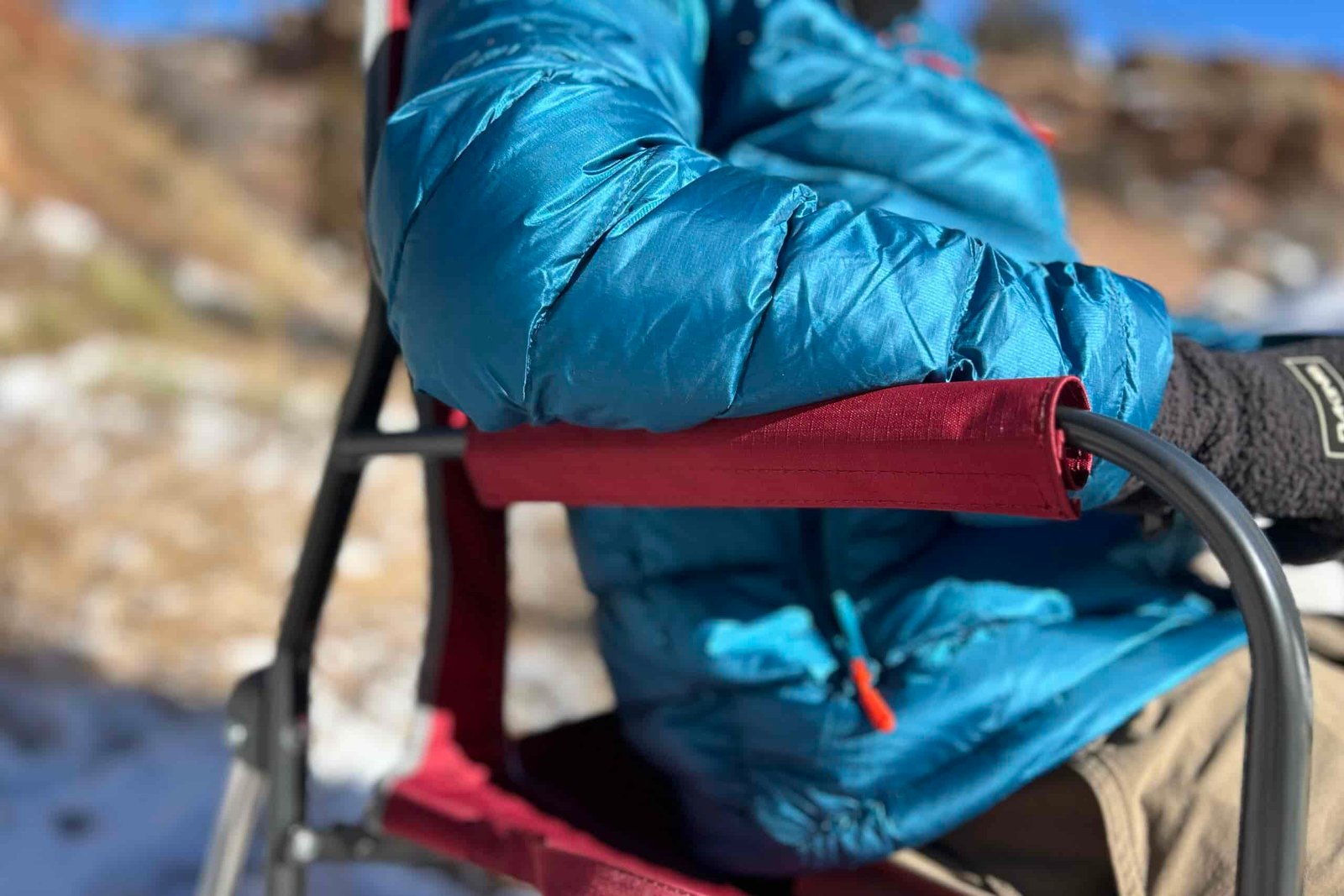 Close up of a person's elbows on the arm rests of a camping chair.
