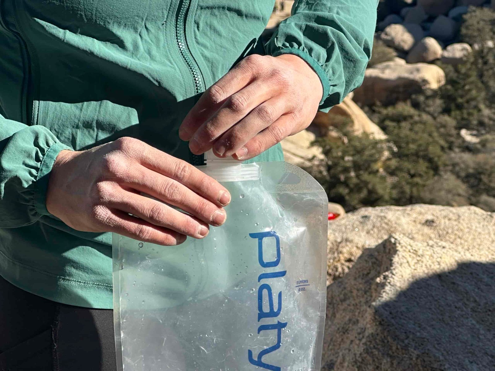Close-up of a hiker holding the Platy and twisting the small cap back on.