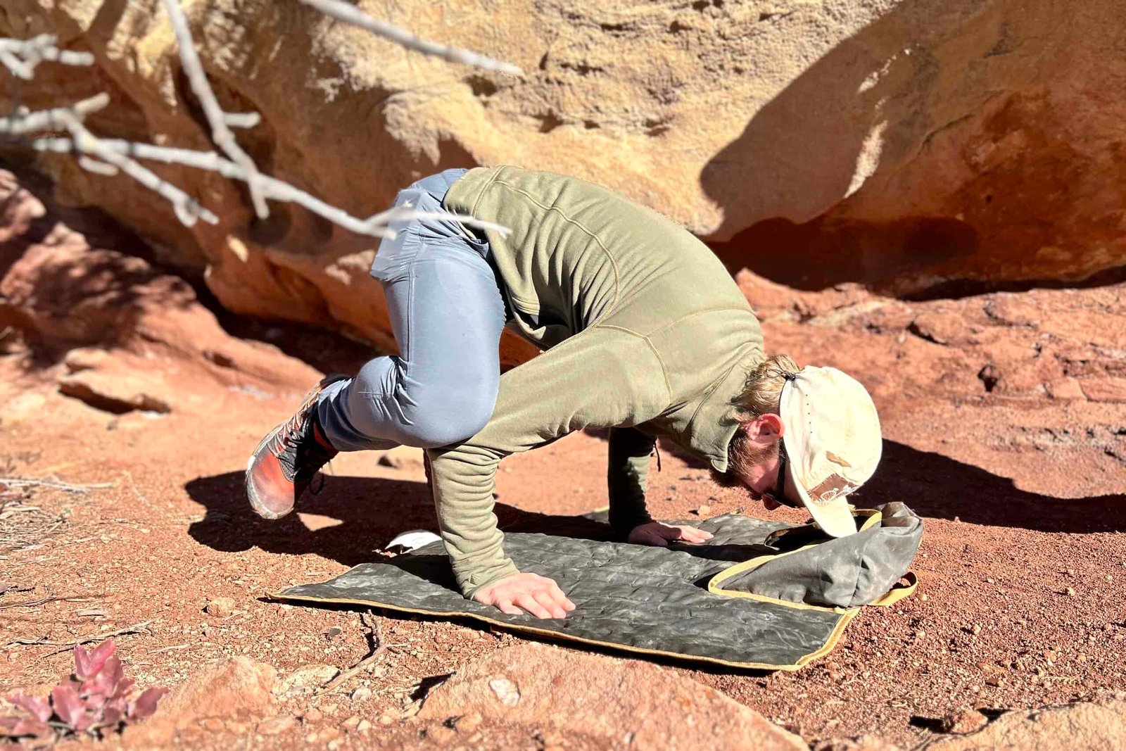 A man does a yoga pose on the flat carrying case of a camping chair.