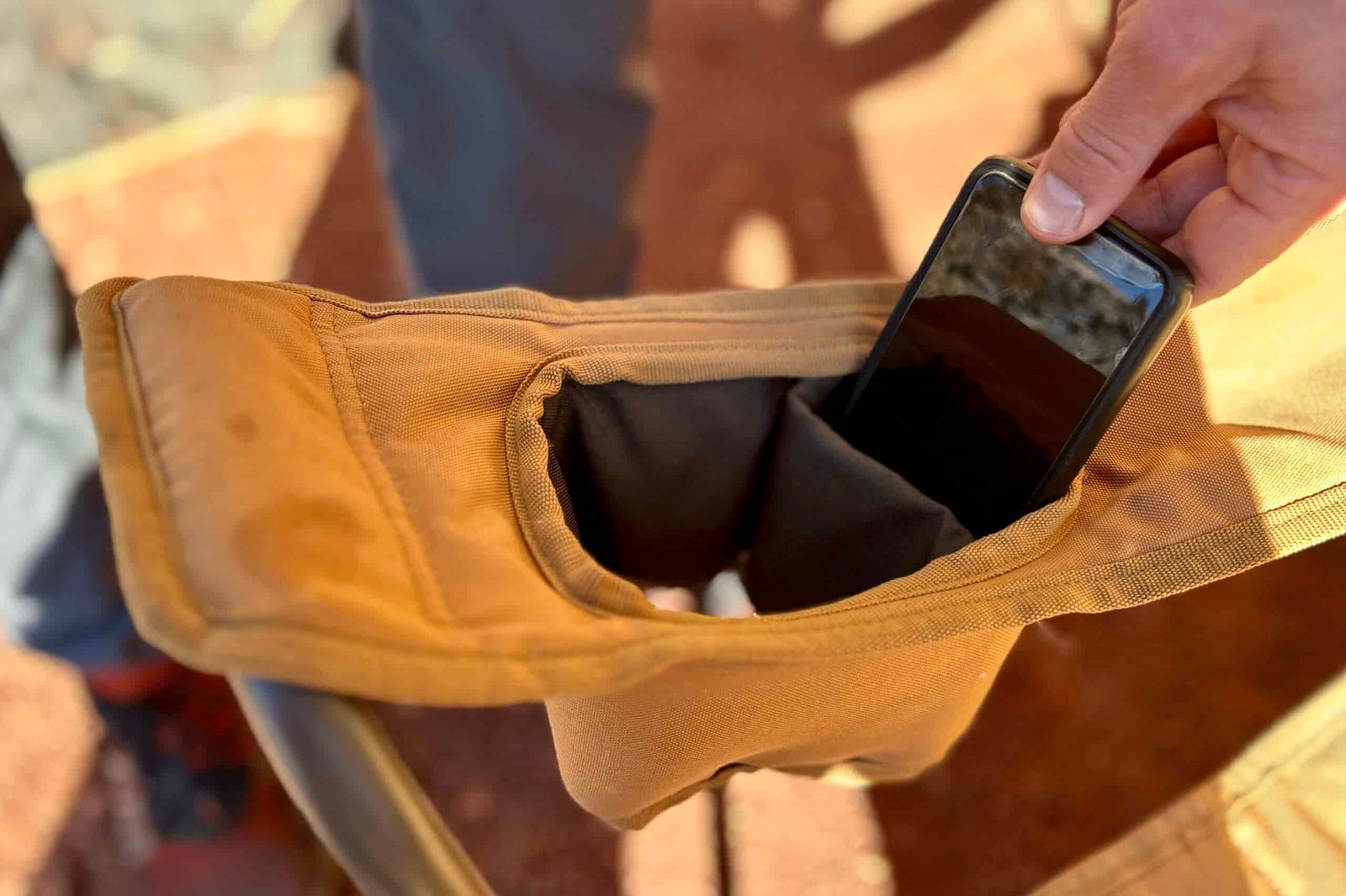 Close up of a phone in a large cupholder in the armrest of a camping chair.