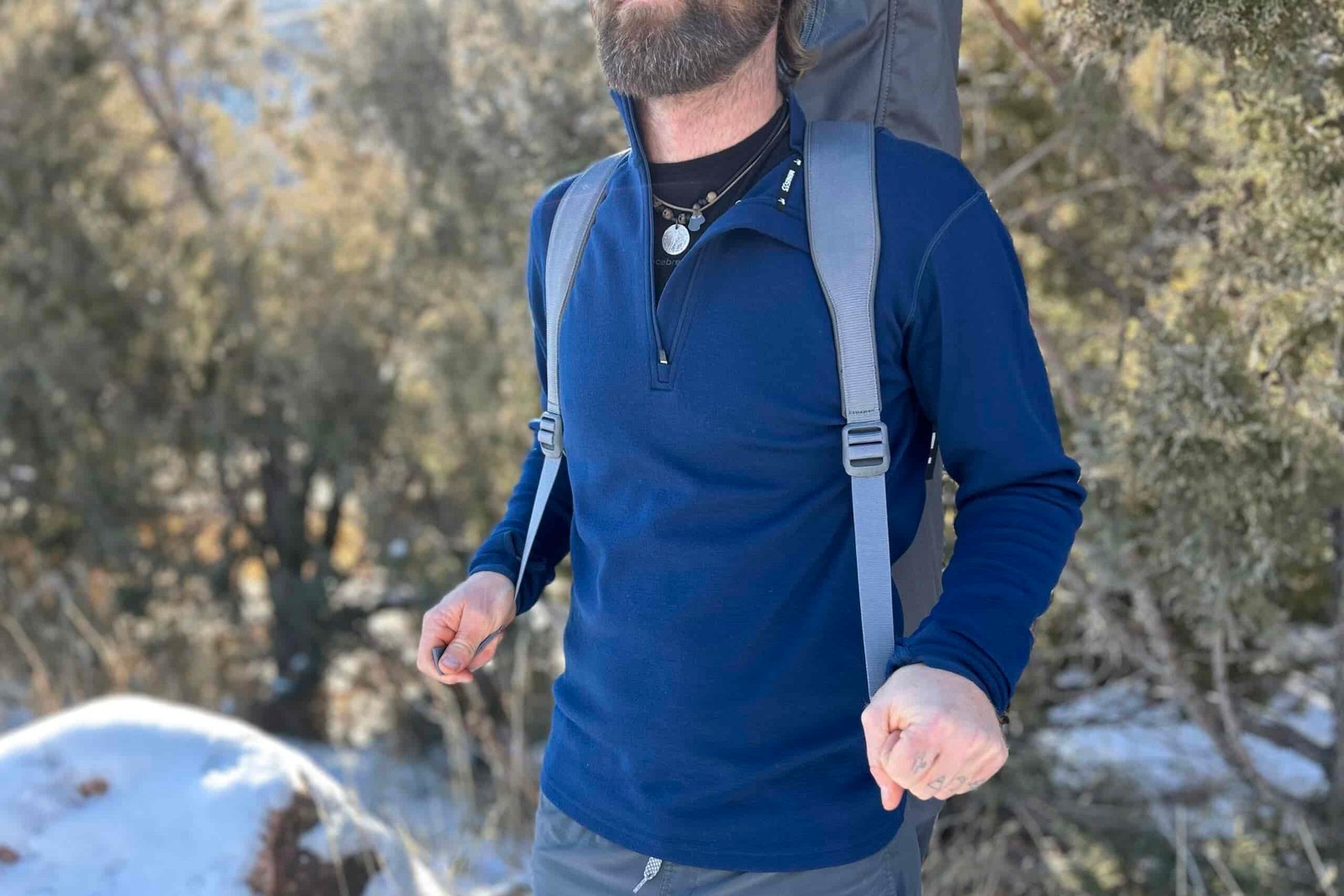 Close up of a man wearing a large camping chair in its case like a backpack.