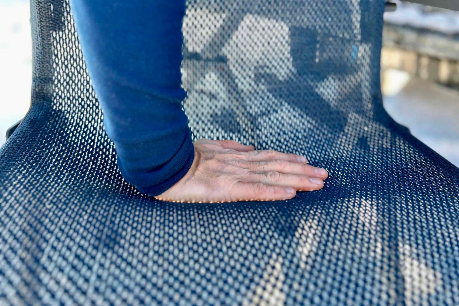 A person pushes their hand into the mesh of a camping chair.