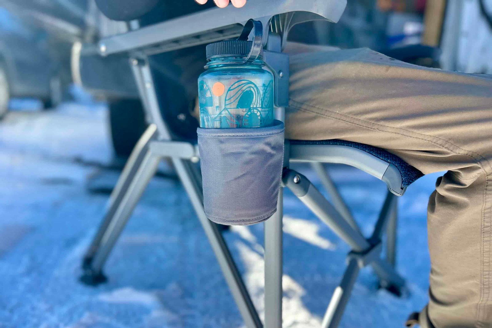 Close up of a Nalgene water bottle in the fabric cupholder of a camping chair.