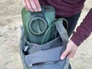 Close up of a hiker loading the Cherainti Bladder into the hydration sleeve of a small backpack