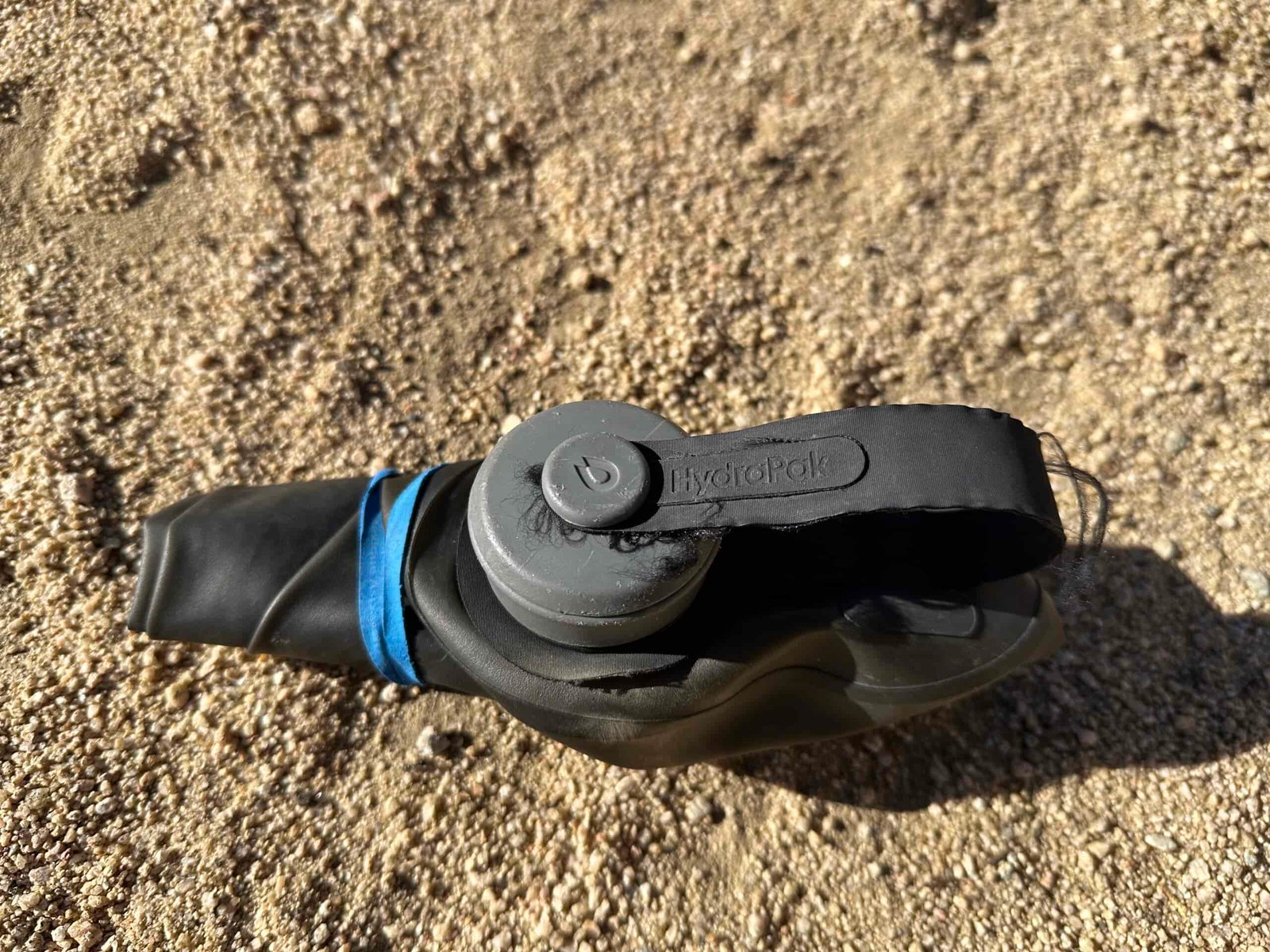 A close up photo shows the HydraPak Seeker water bag rolled up and secured with a rubber band.