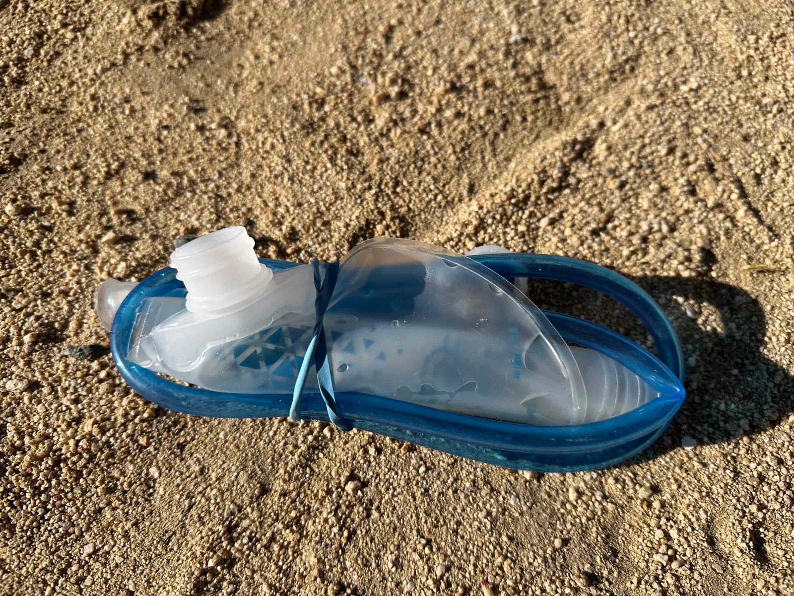 Close up photo of the Platypus Hoser Reservoir emptied out, rolled up and secured with a rubber band, showing its small packed size.