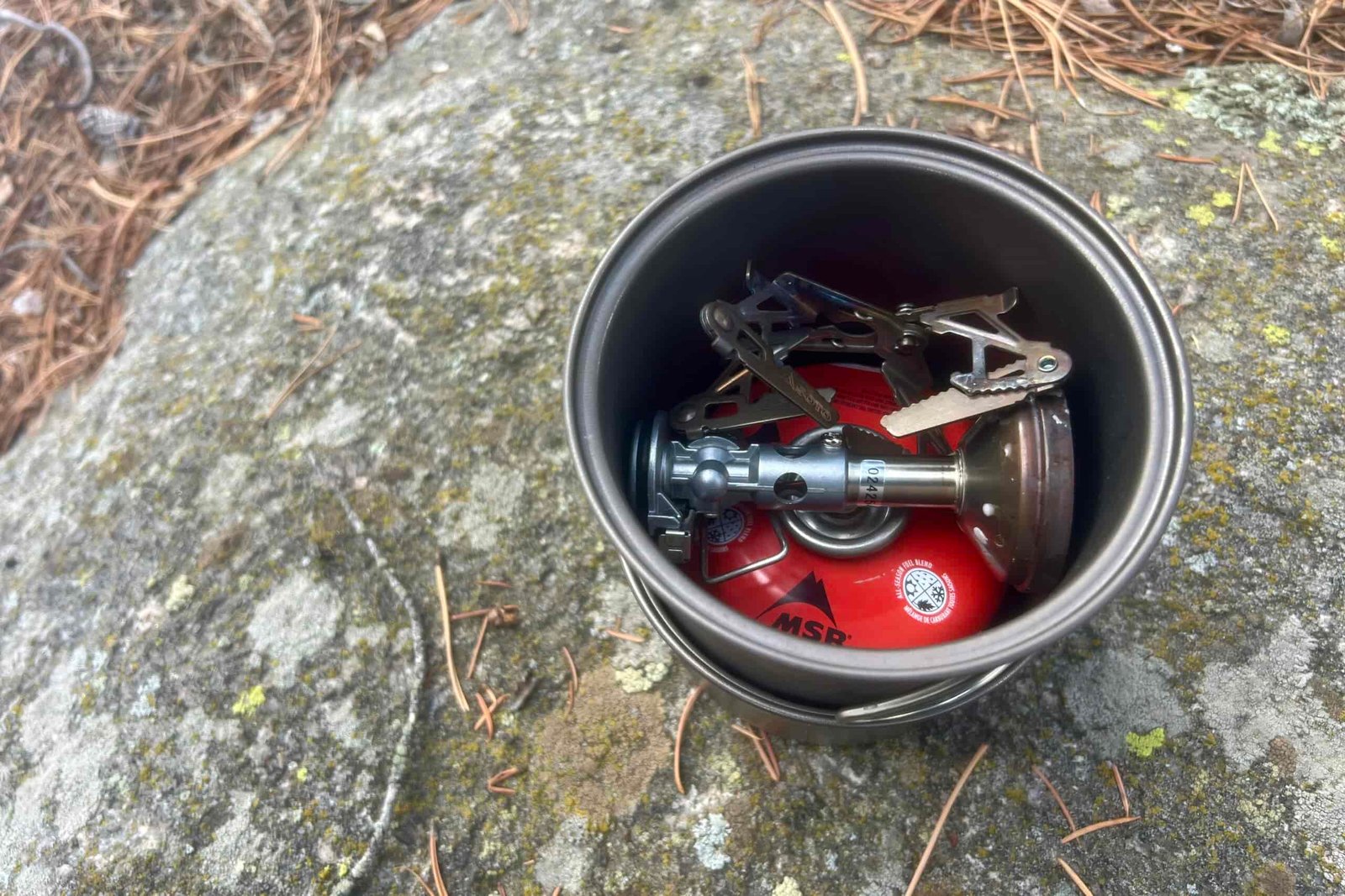 a top down view of a fuel canister and backpacking stove packed into a backpacking cook pot.