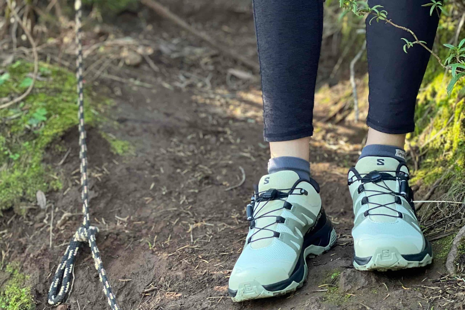 Close up of a woman standing on a trail wearing the Salomon X Ultra 4 shoes.