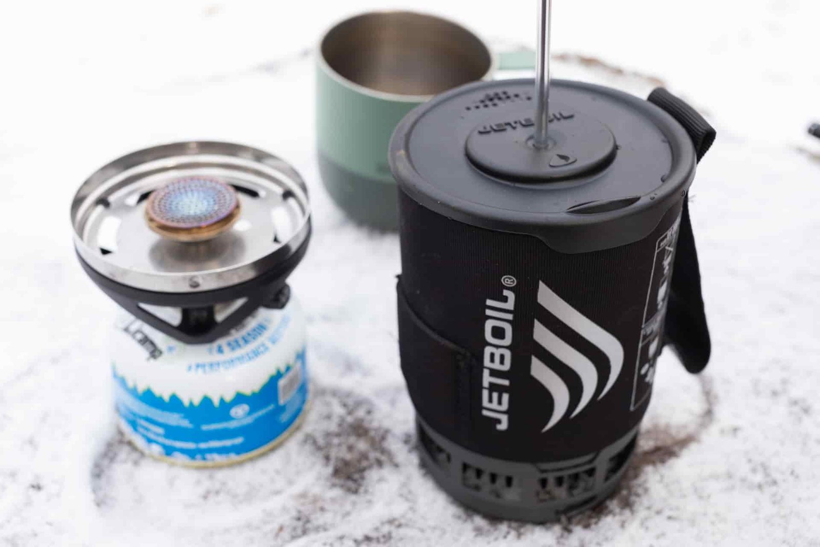 A Jetboil Silicone Coffee Press sits next to a stove waiting to be pressed.