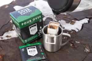 Water pours into a Kuju coffee pouch sitting in a mug.