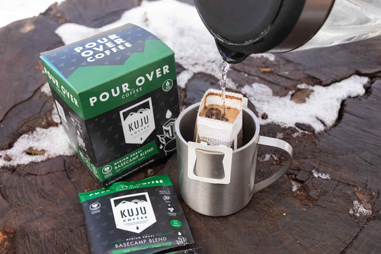Water pours into a Kuju coffee pouch sitting in a mug.
