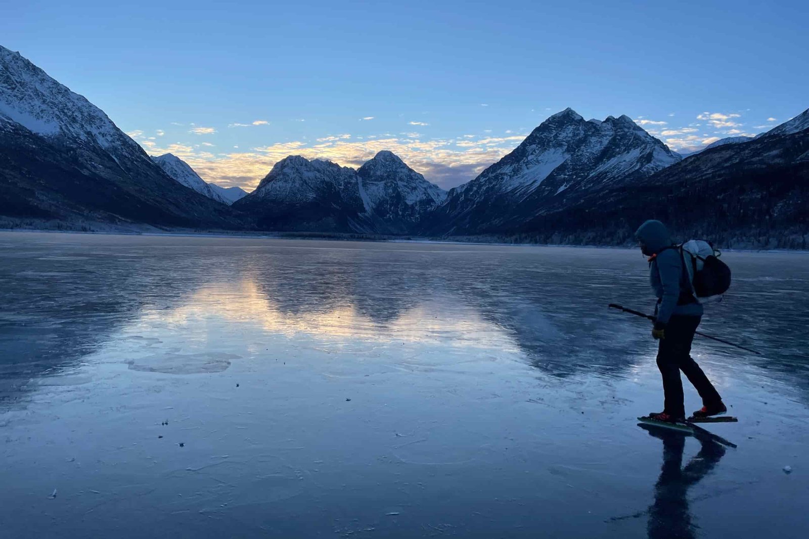 A man ice skates at sunrise with a mountain view