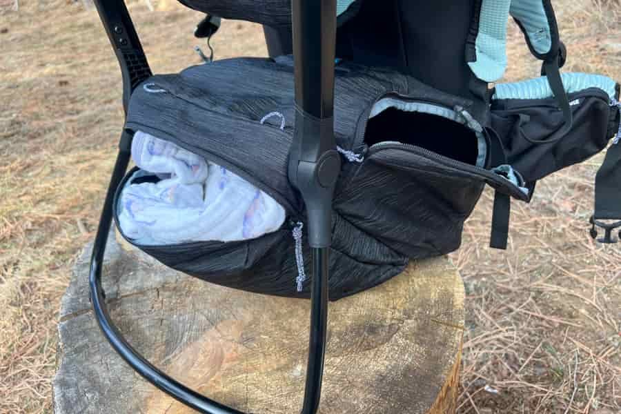 Close-up view of the Thule Sapling's large lower zippered storage compartment with a soft blanket partially packed inside.