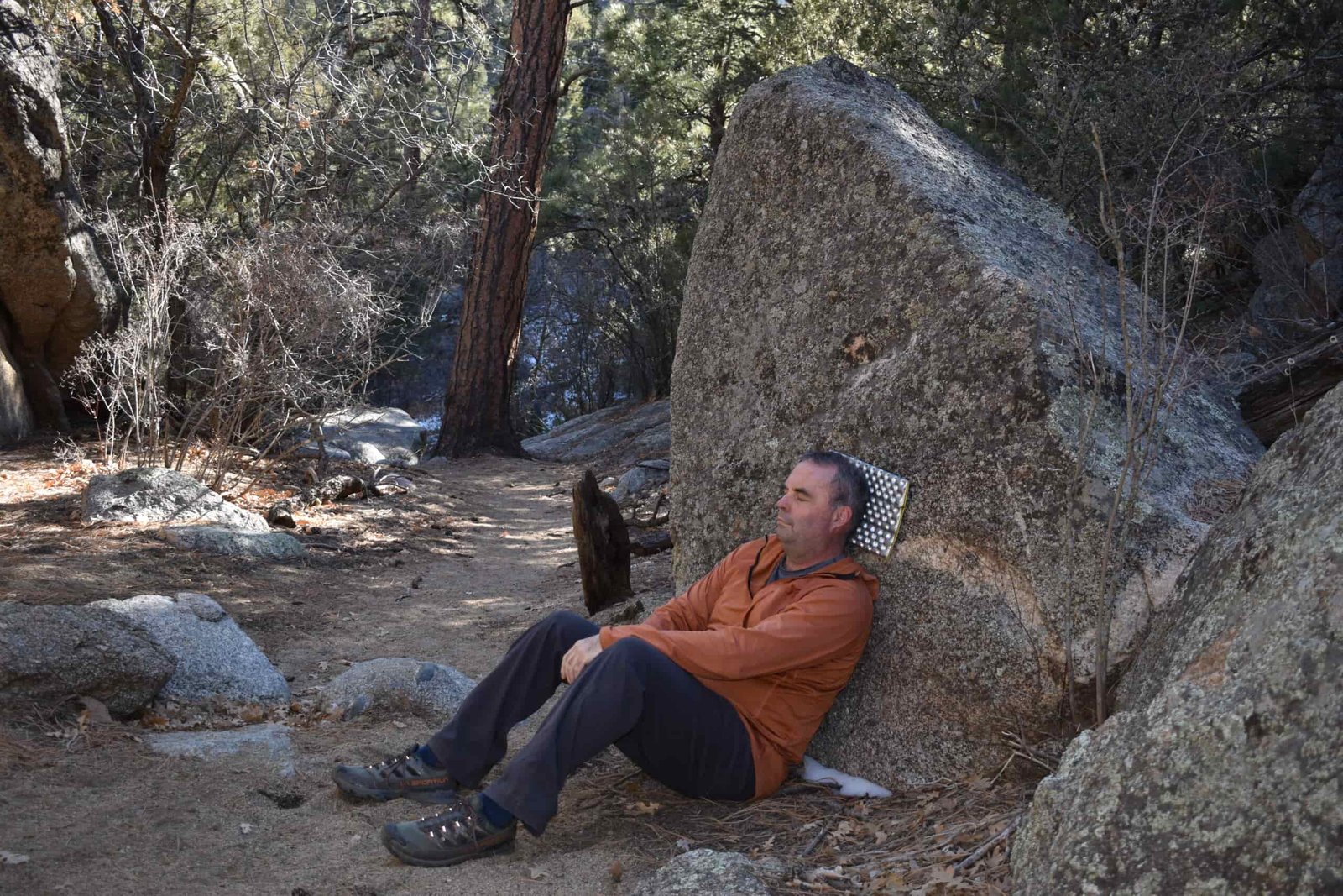 Hiker's head rests against the Z-Seat while he leans back against a boulder to rest
