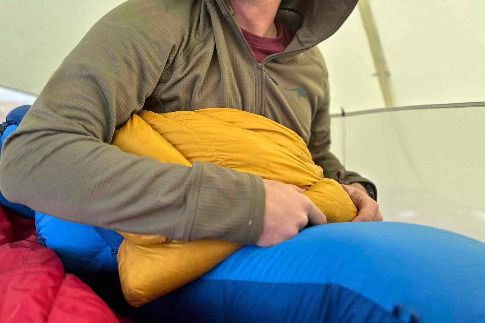 Close-up image of a person in a sleeping bag holding onto the cushy baffles of the top of a sleeping bag while they're inside.