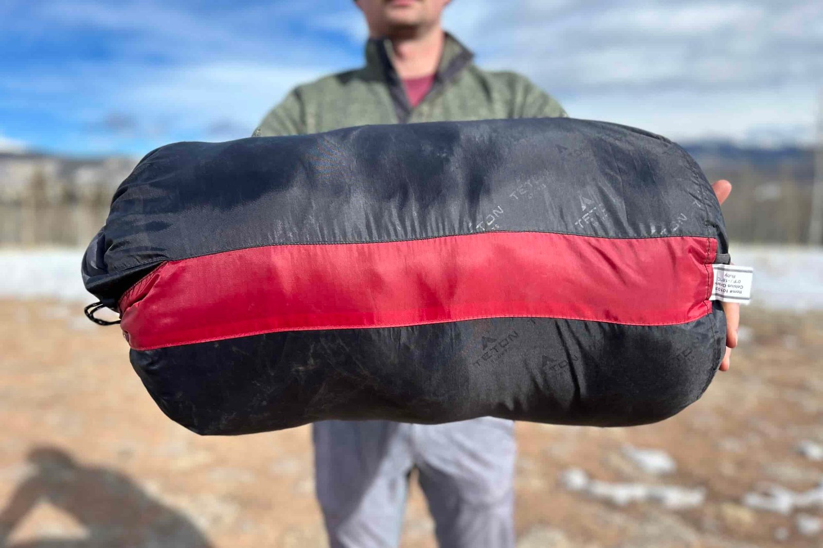Close-up image of the side of a sleeping bag held up by someone longways.