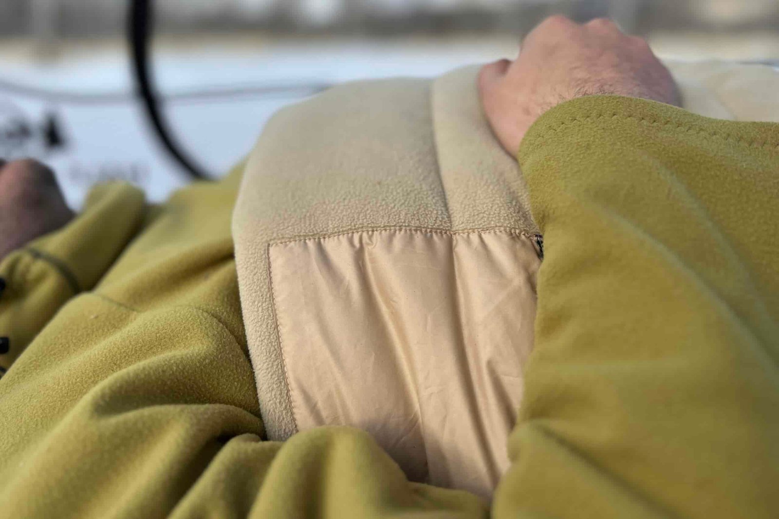 Close up image of the cushy internal fabric of a sleeping bag with a person's hand and arm on top.
