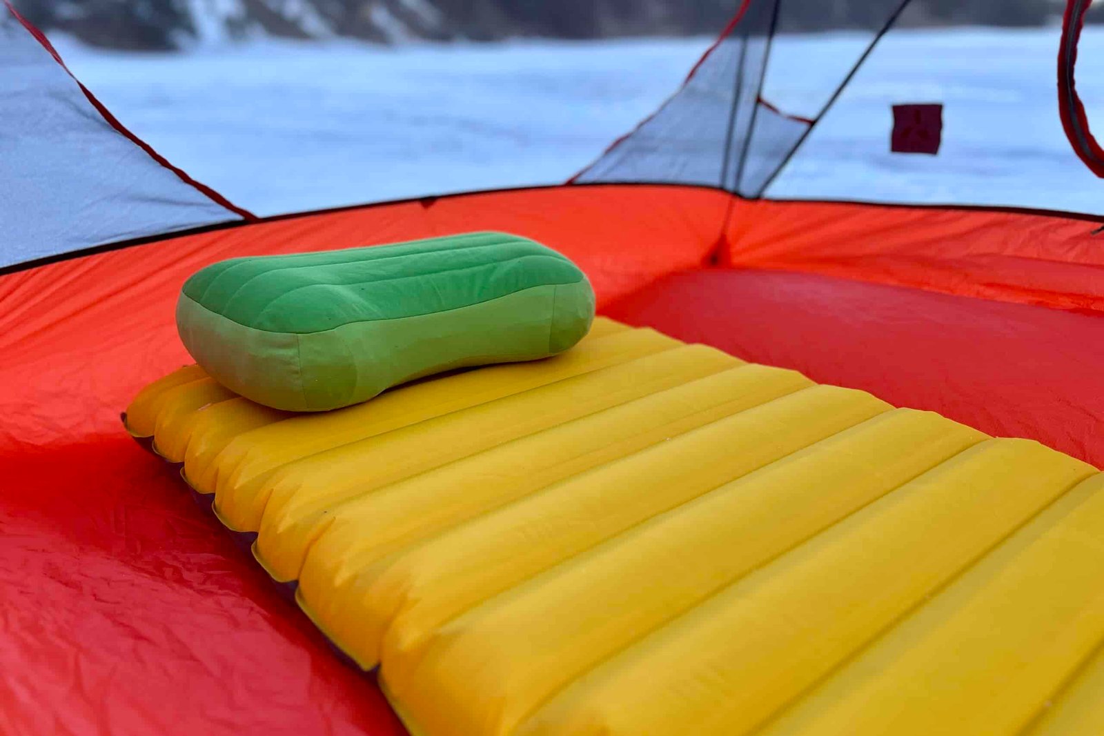 A camping sleeping pad in a tent with a camping sleeping pillow.