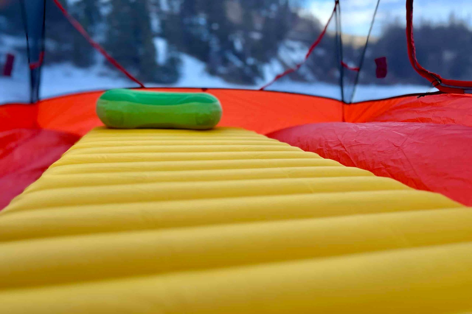 Close-up image of the wide, thick baffles of a camping sleeping pad inside of a tent with a backpacking pillow at the top.