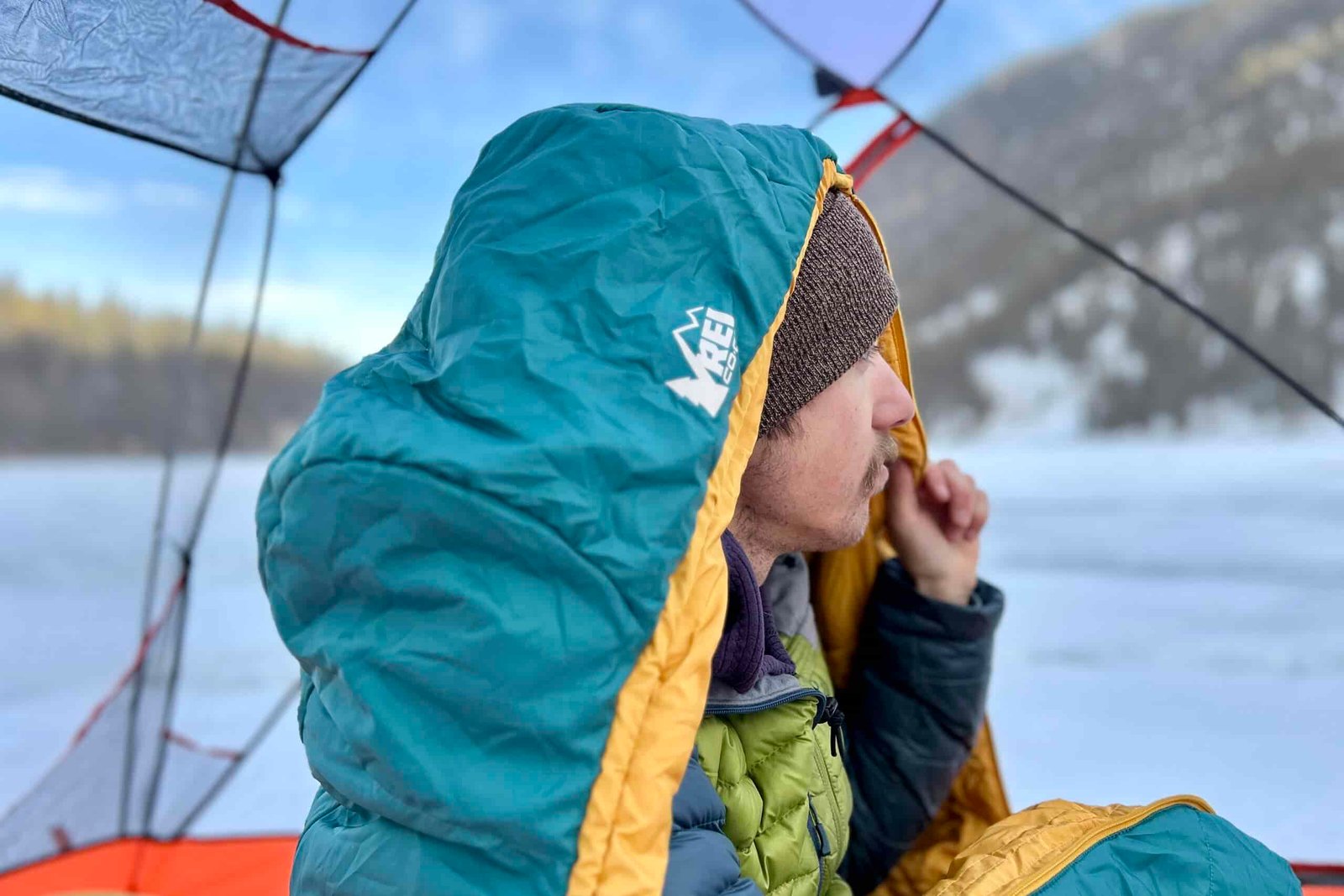 Close up image of a man in a sleeping bag with the hood up over his head.