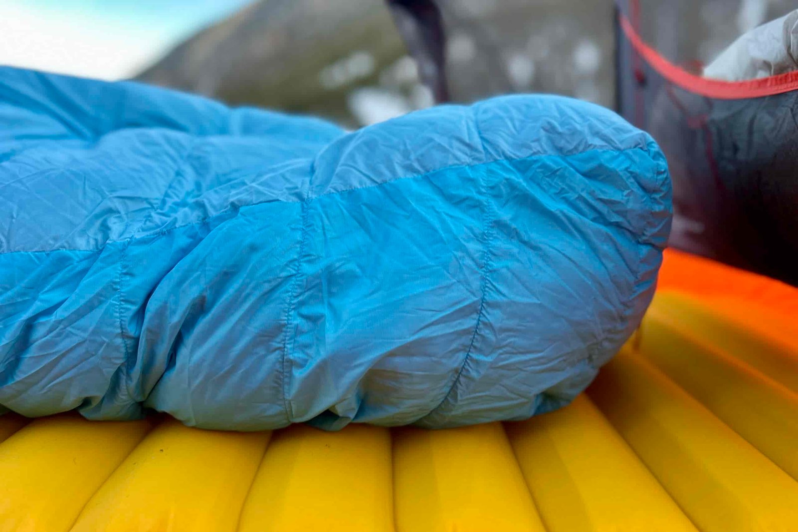 Close up image of the footbox of a sleeping bag on a pad in a tent in a wintry setting.