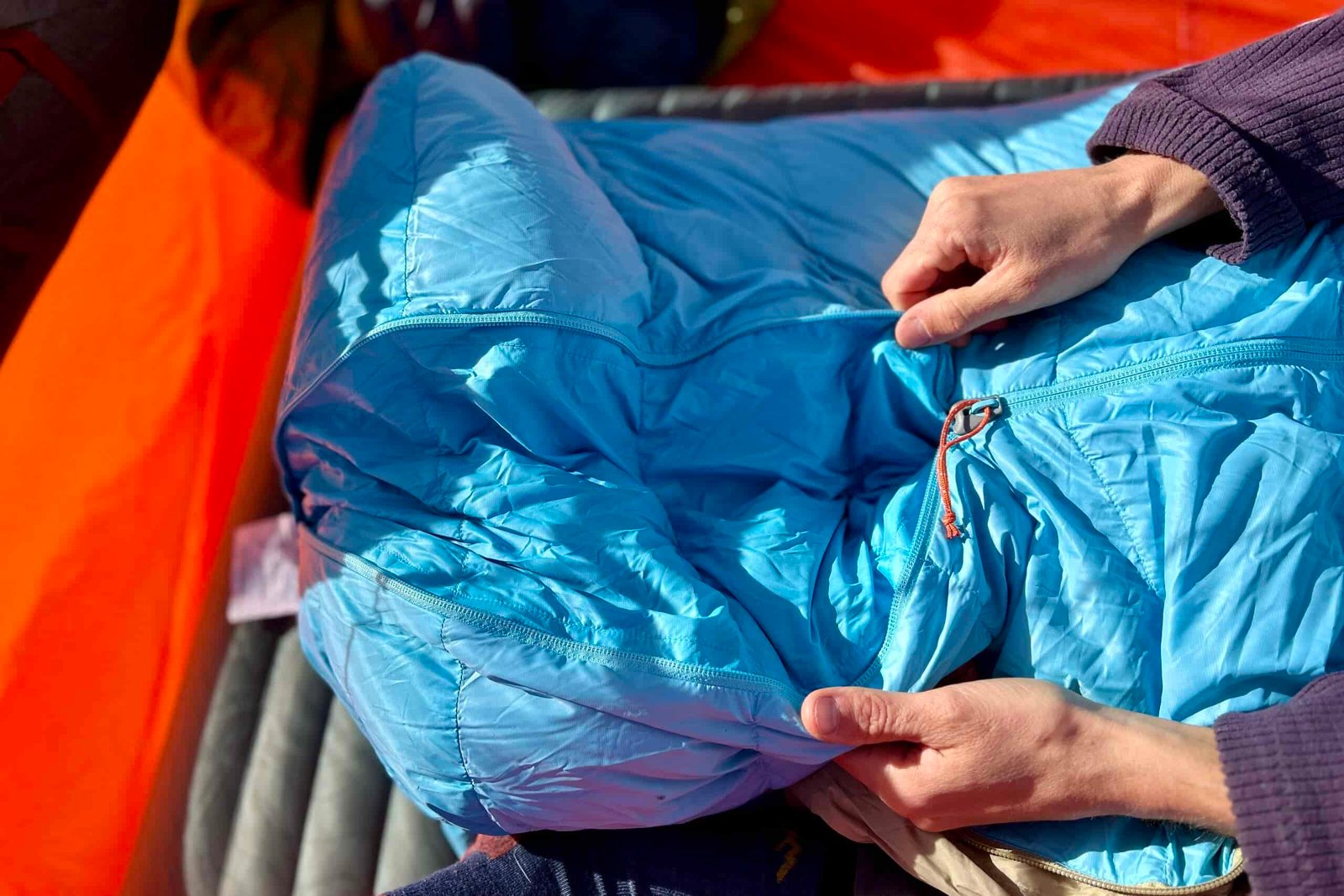 Close up image of a person unzipping a sleeping bag.