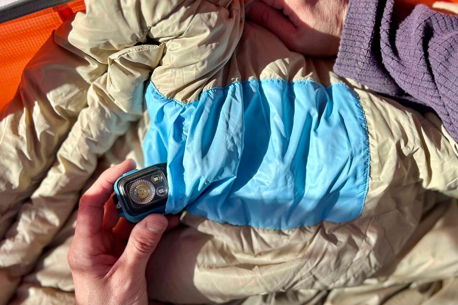 Close up image of a hand pulling a headlamp out of a large internal pocket.