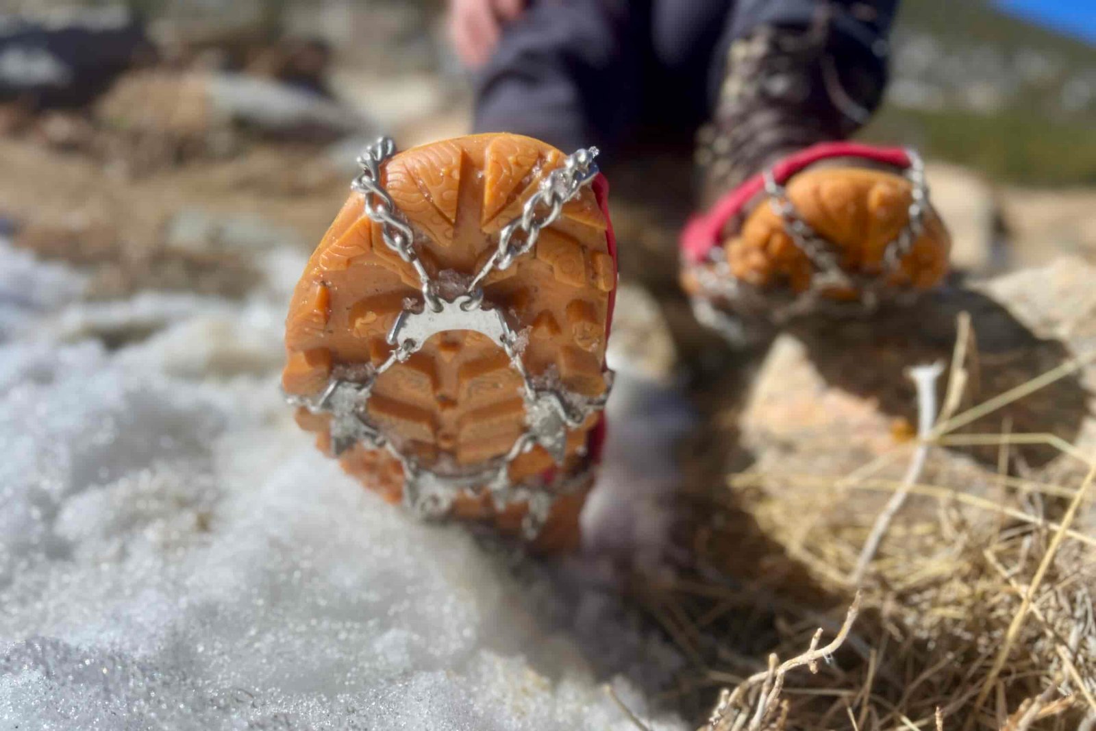 A close up of feet facing the camera wearing boots and ice cleats.