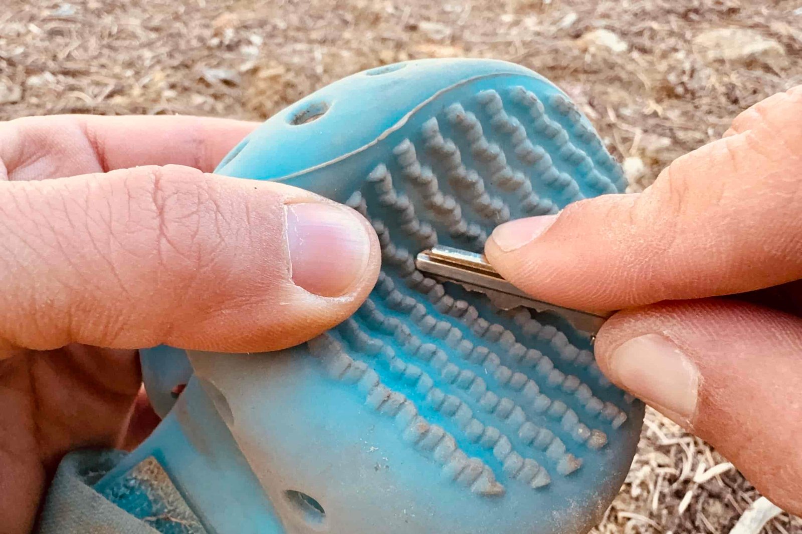 A close up of a hand scraping a WagWellies boot with a house key.