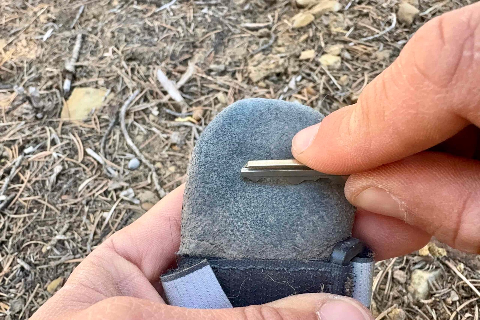 A close up of a hand scraping a Muttluks boot with a house key.