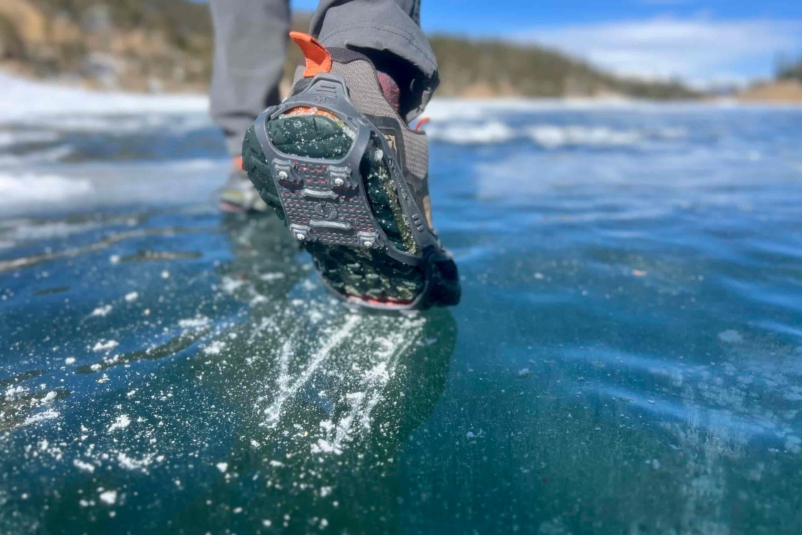 A close up of a foot scraping on ice with a pair of ice cleats.