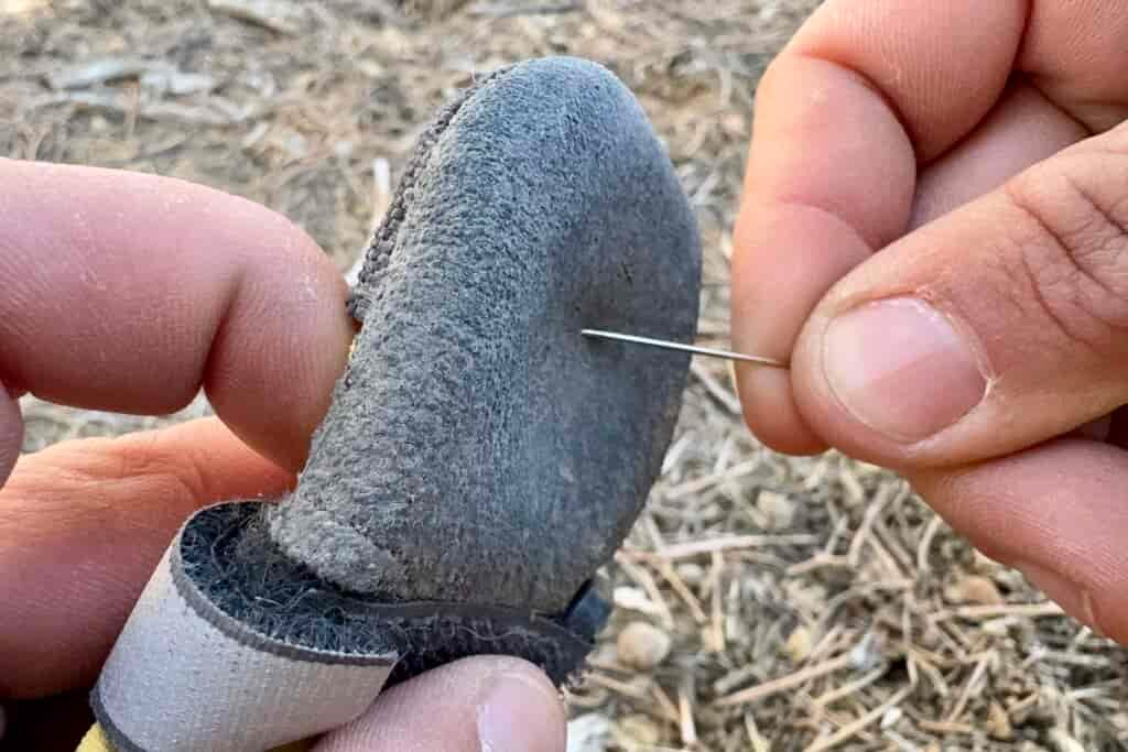 Close up of a Muttluks boot being poked with a sewing needle.