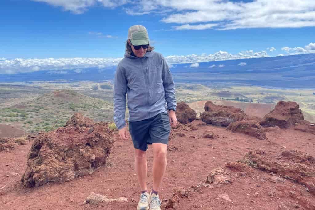 A man walks along an alpine ridge wearing a windbreaker.