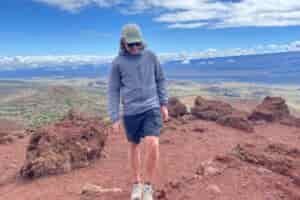 A man walks along an alpine ridge wearing a windbreaker.