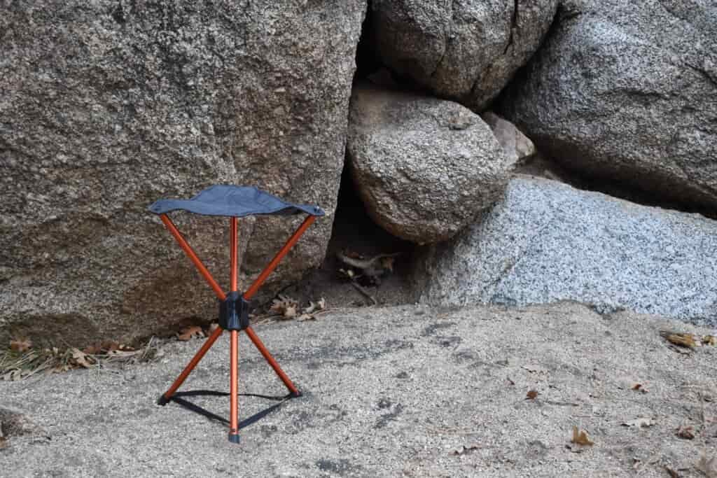 REI stool set up on the stand in front of gray boulders