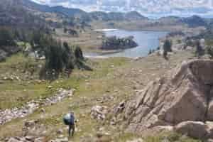 A woman hikes off trail through alpine scenery