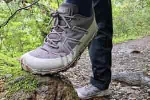 Person stepping up on a rock, showing the creasing of her shoe’s upper material where her foot bends.