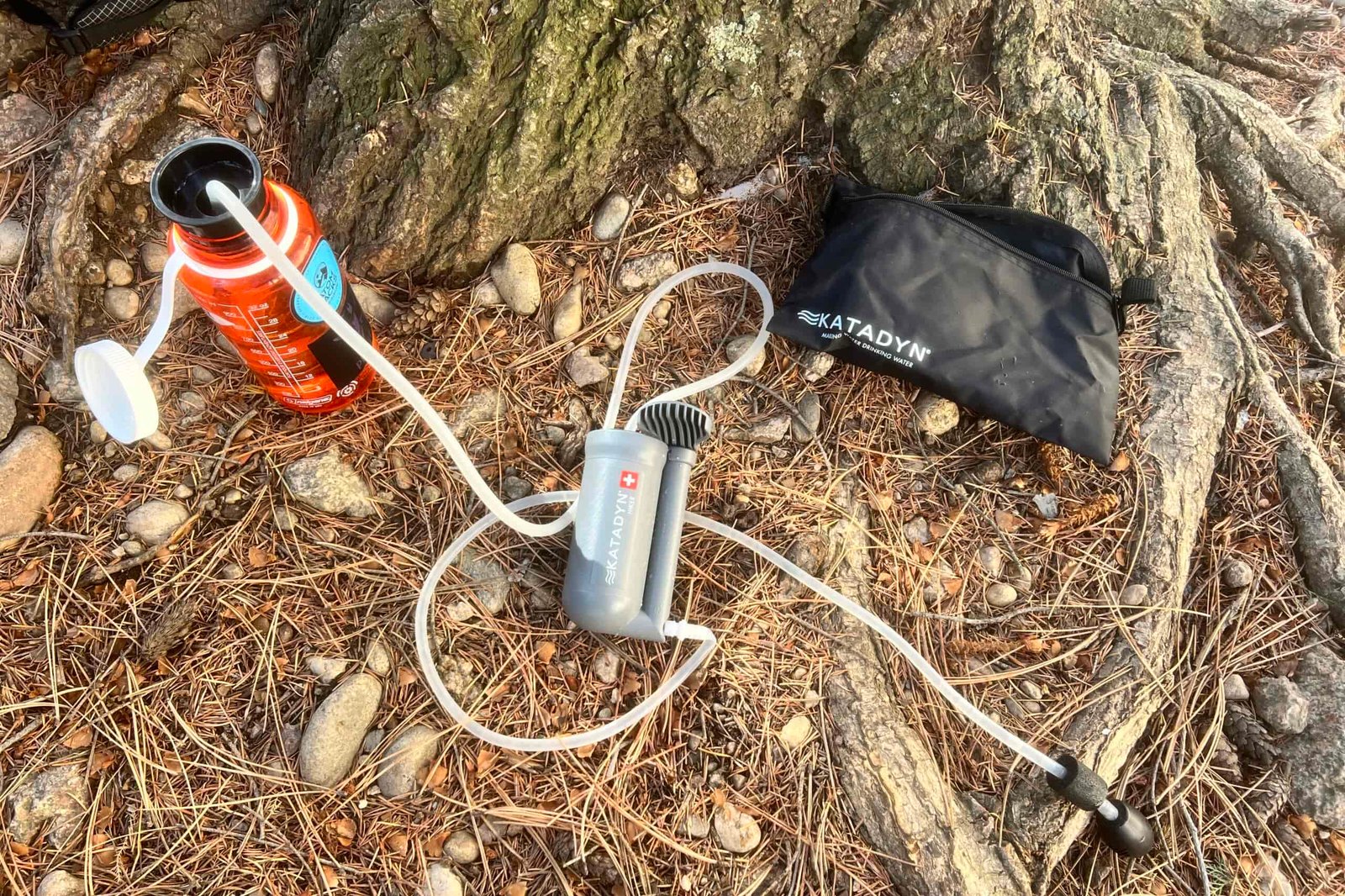 The components of the katadyn hikder filter lay on piney ground next to a tree