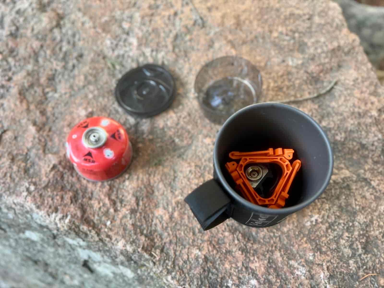 A top down view of the jetboil flash on a rock with some components in the pot and others on the rock.