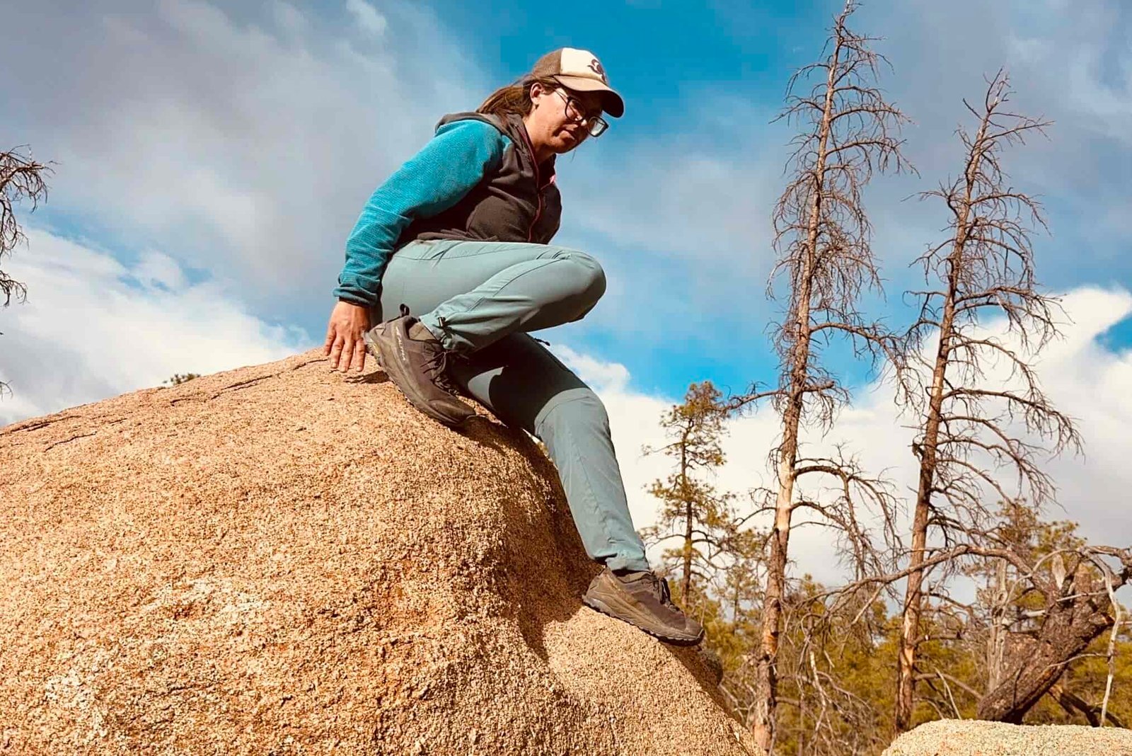 A person wearing the Baleaf pants is scrambling down a rock in the woods.