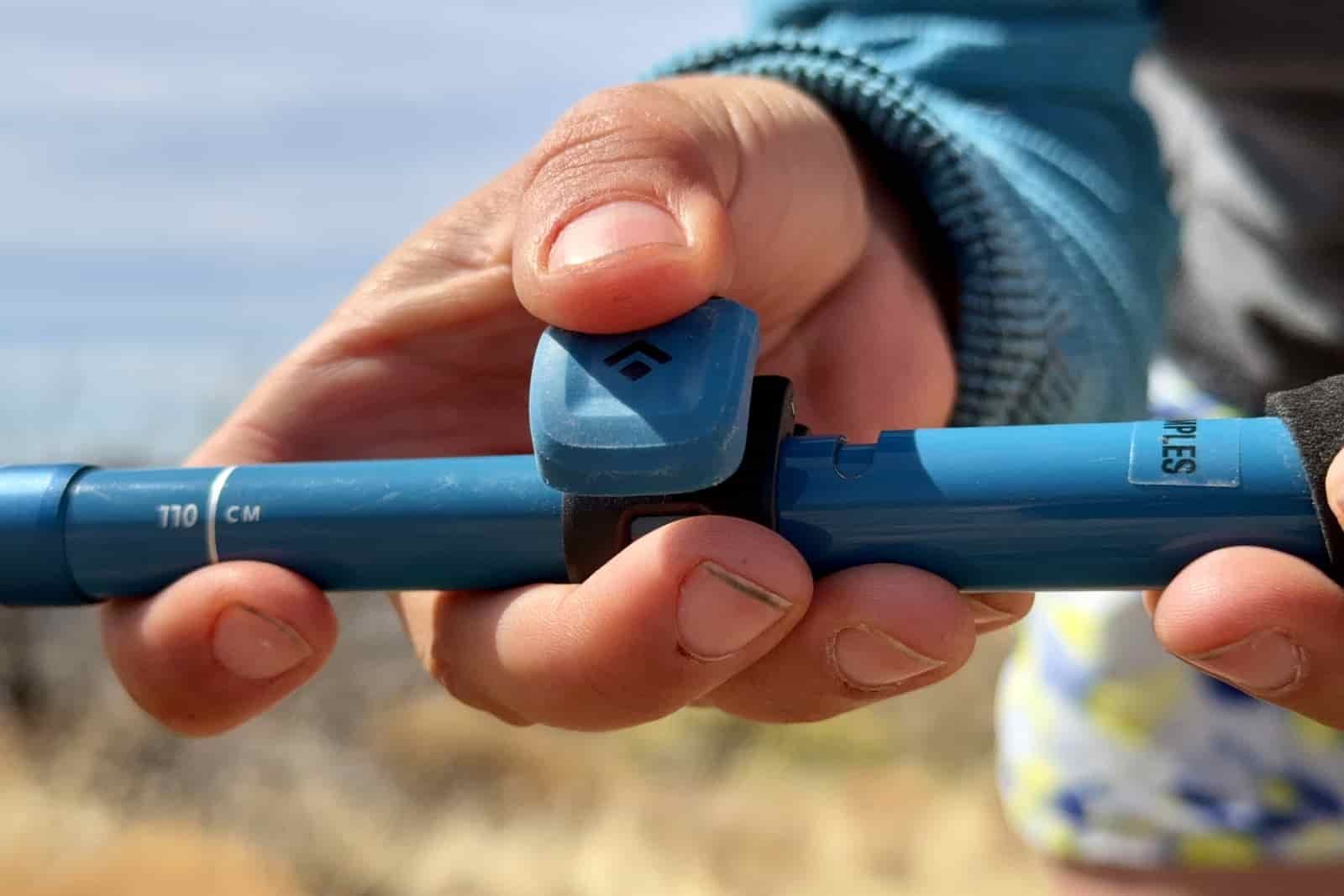 A close up of a person's hand closing the flick lock on the Distance Carbon trekking poles.