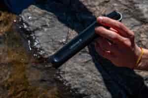 A close up of a hand holding a straw water filter