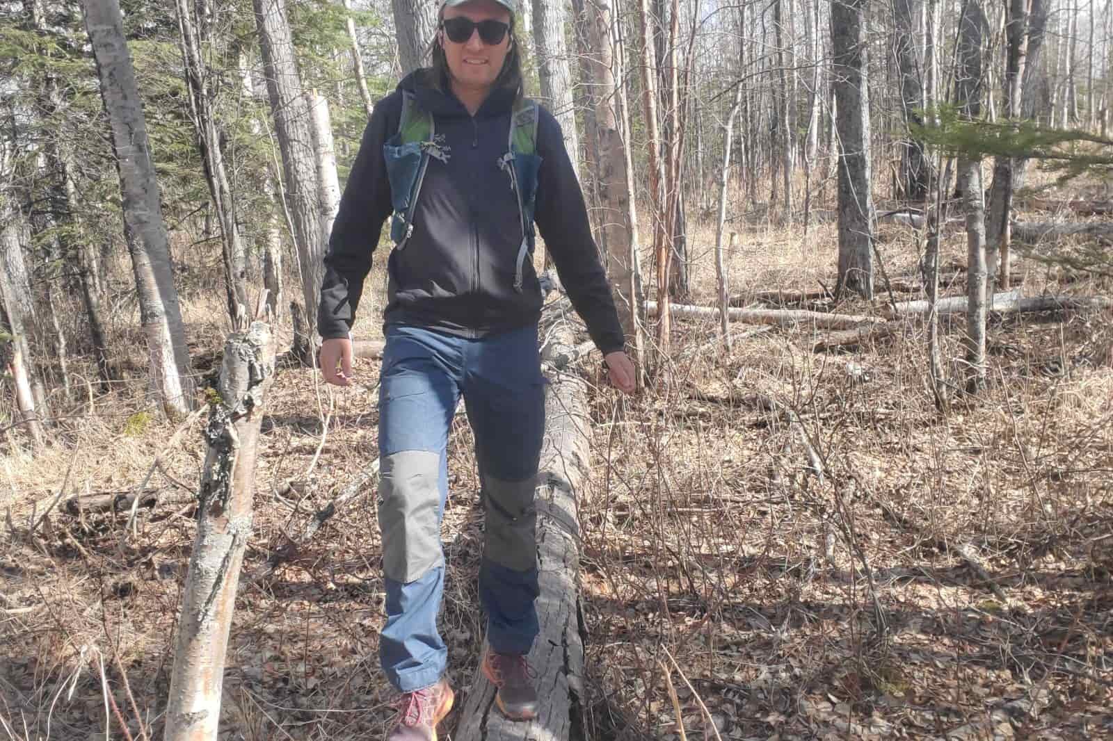 A man walk along a fallen log.