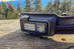a closeup of a headlamp sitting on a stump in a forest.